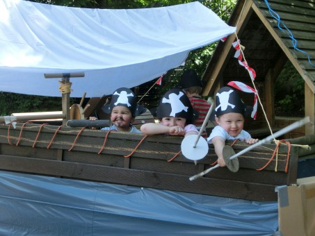 Drei Kinder mit Piratenhüten sitzen in einem selbstgebastelteten Piratenschiff.