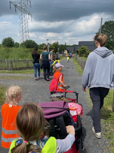 Kinder und Erwachsene gehen zum Mühlenhof und ziehen einen Bollerwagen.