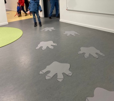 Dinosaurierspuren aus Papier auf dem Boden.