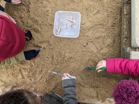 Kinder graben Dinosaurierknochen aus Sand aus.