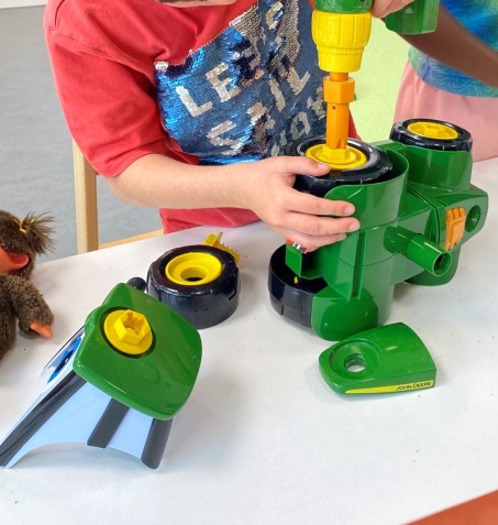 Ein grüner Spielzeugtraktor wird zusammengebaut.