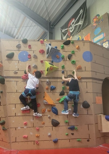 Zwei Kinder klettern an einer Wand.