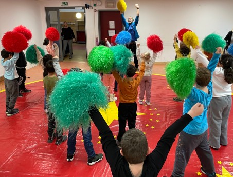 Kinder tanzen mit bunten Pompoms.