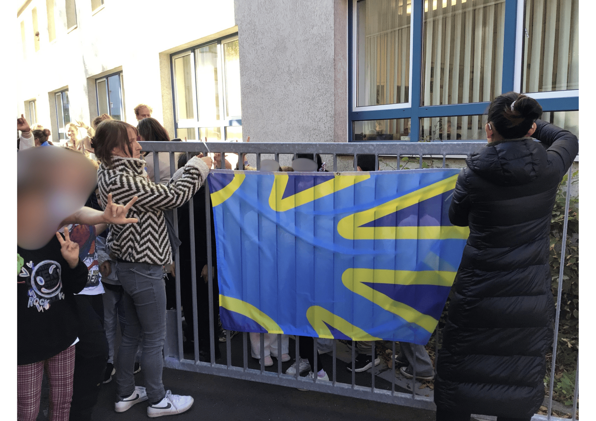 Schulleiterin und Koordinatorin befestigen die Gehörlosenflagge am Schultor.