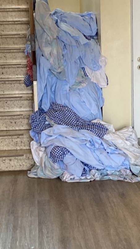 Ein Haufen schmutziger Bettwäsche neben einer Treppe.