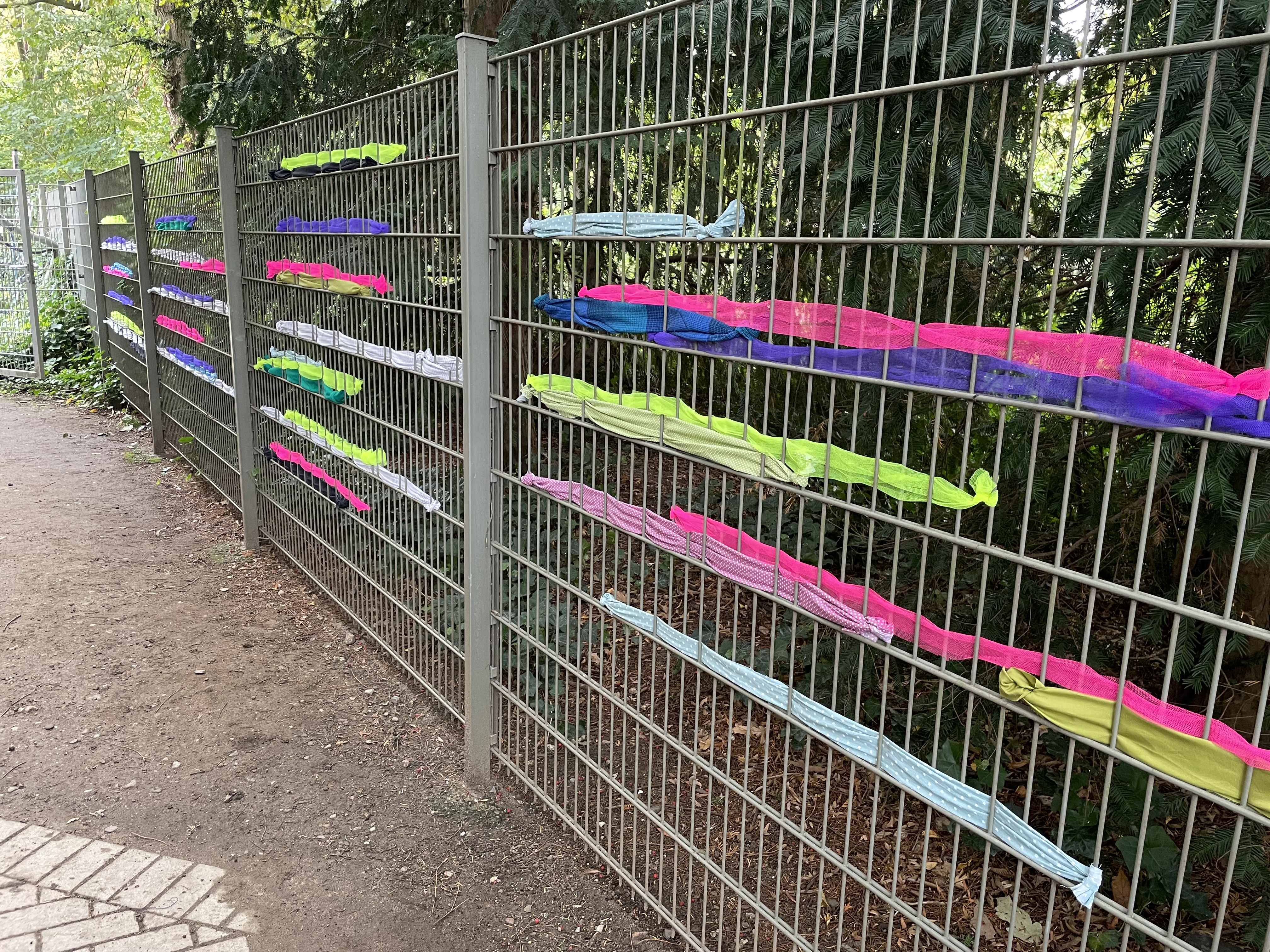 Zaun mit bunten Stoffstreifen.