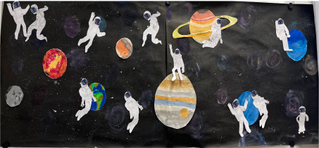 Bunte Bilder von Planeten und Astronauten aufgeklebt auf einen schwarzen Hintergrund.