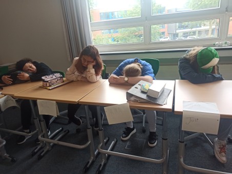 4 Schüler*innen sitzen sehr müde an ihren Tischen und legen die Köpfe auf die Tische.