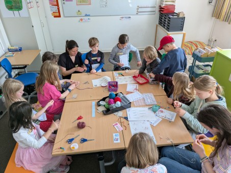 Viele Kinder sitzen um einen Tisch und arbeiten kreativ.
