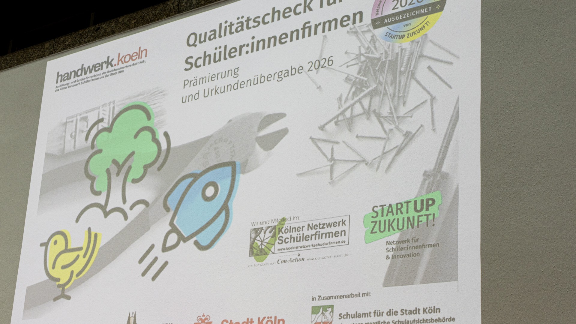Foto vom Titel der Veranstaltung, mit einem Beamer an eine Wand projiziert. 