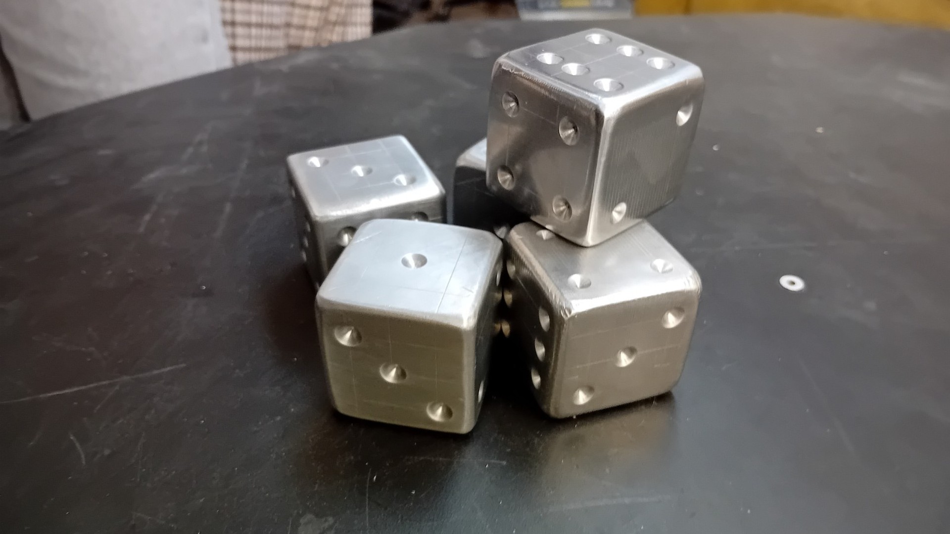 Auf einem Tisch liegen vier große Würfel aus Metall