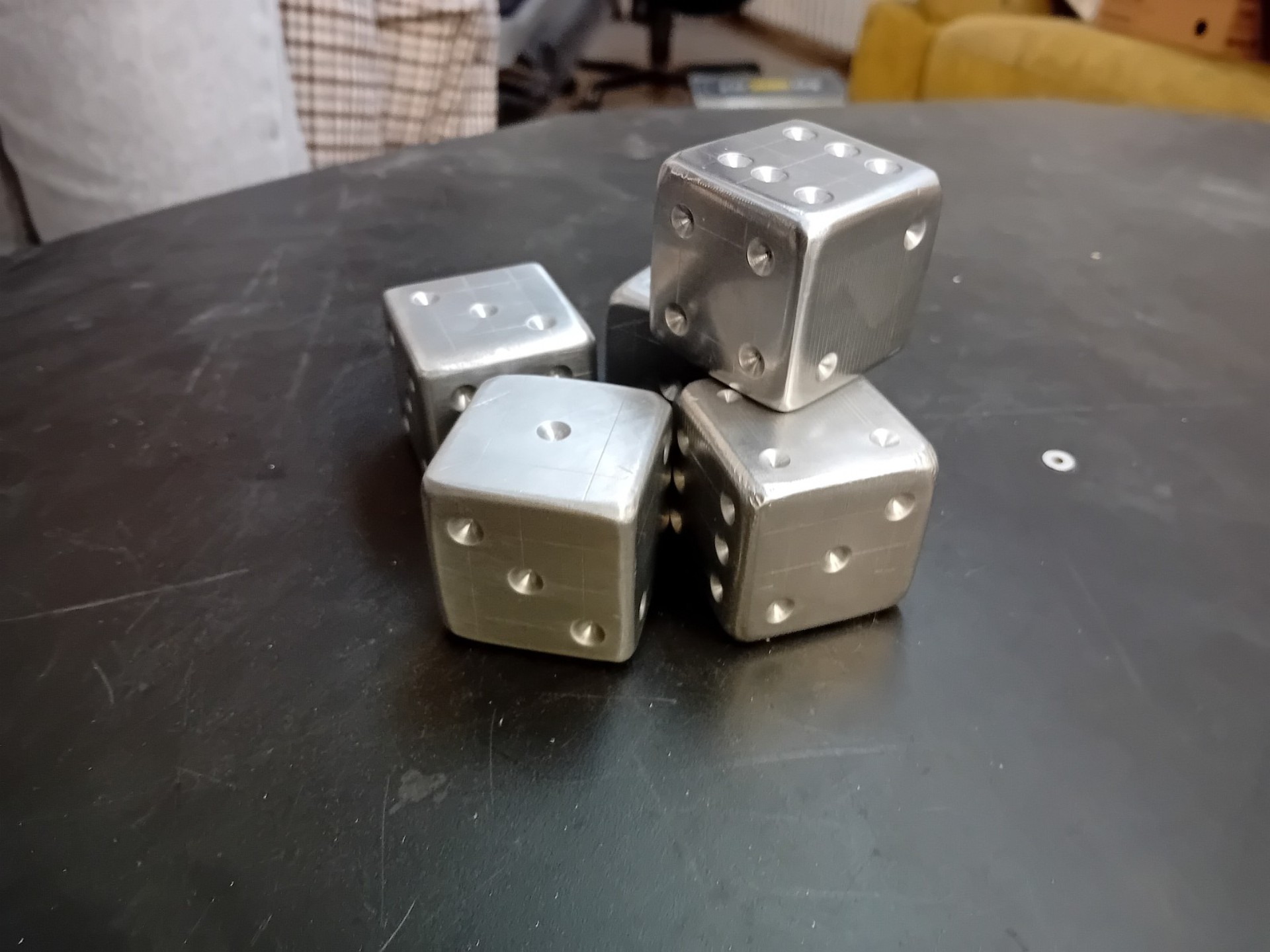 Auf einem Tisch liegen vier große Würfel aus Metall