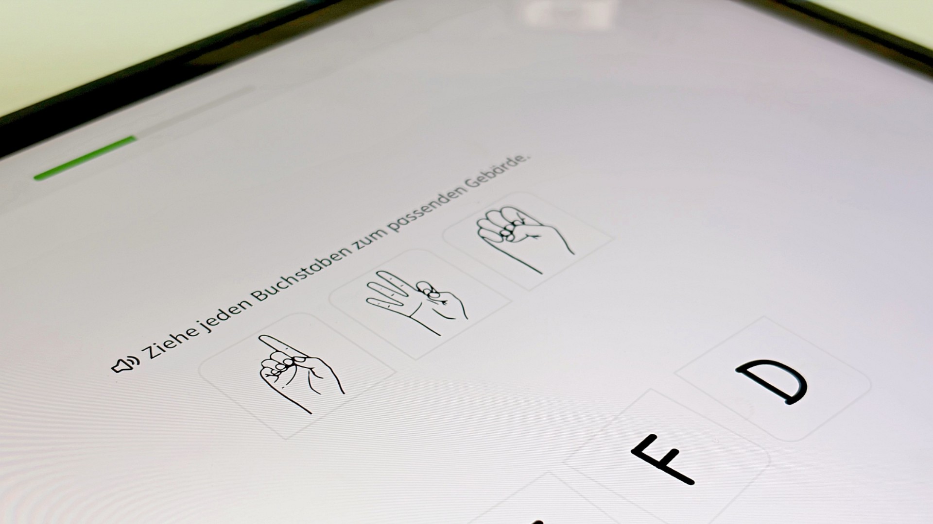 Bildschirm eines Tablets mit einer Übungzur Gebärdensprache: "Ziehe jeden Buchstaben zur passenden Gebärde"