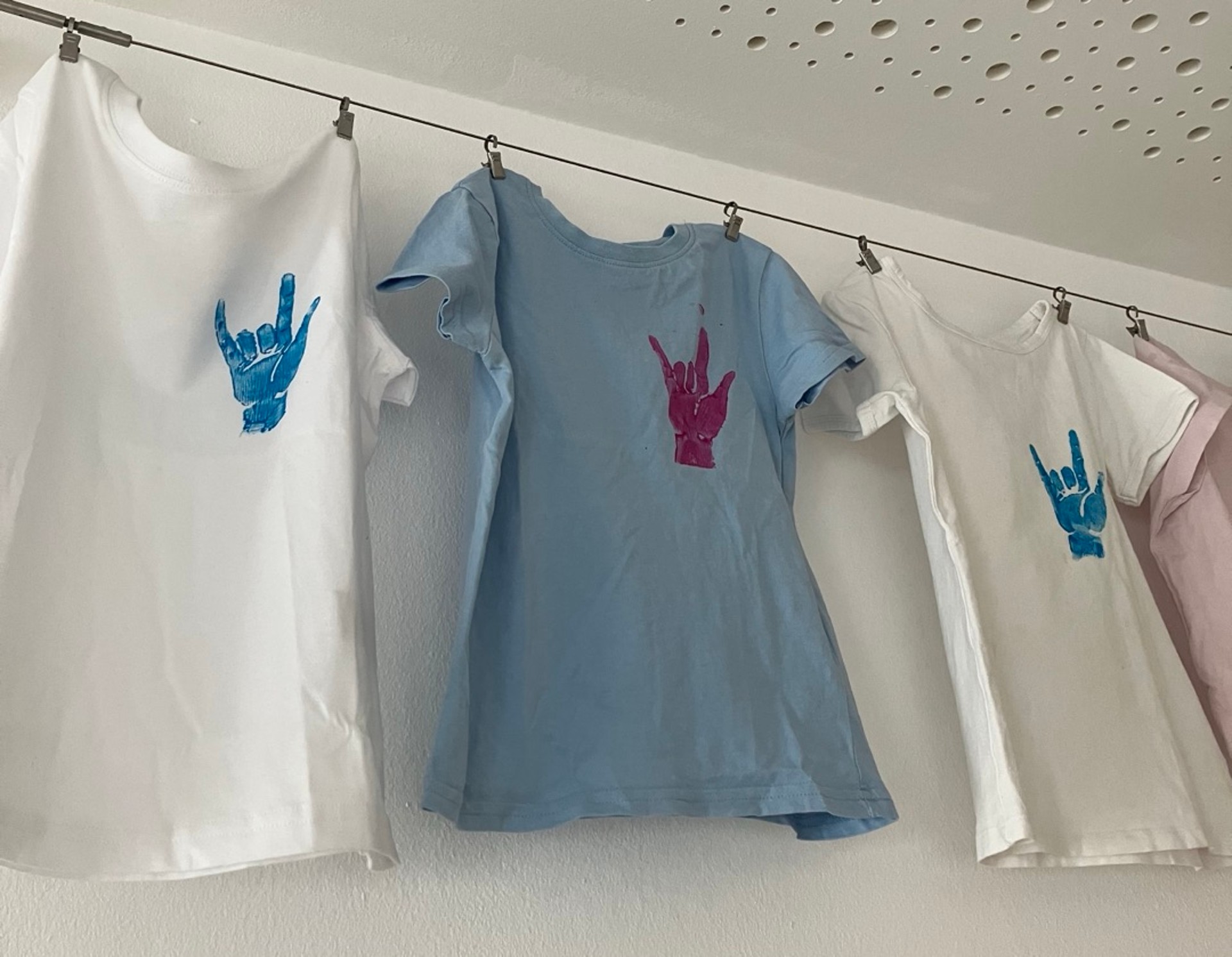 Bedruckte T-Shirts hängen auf Bügeln zum Trocknen.