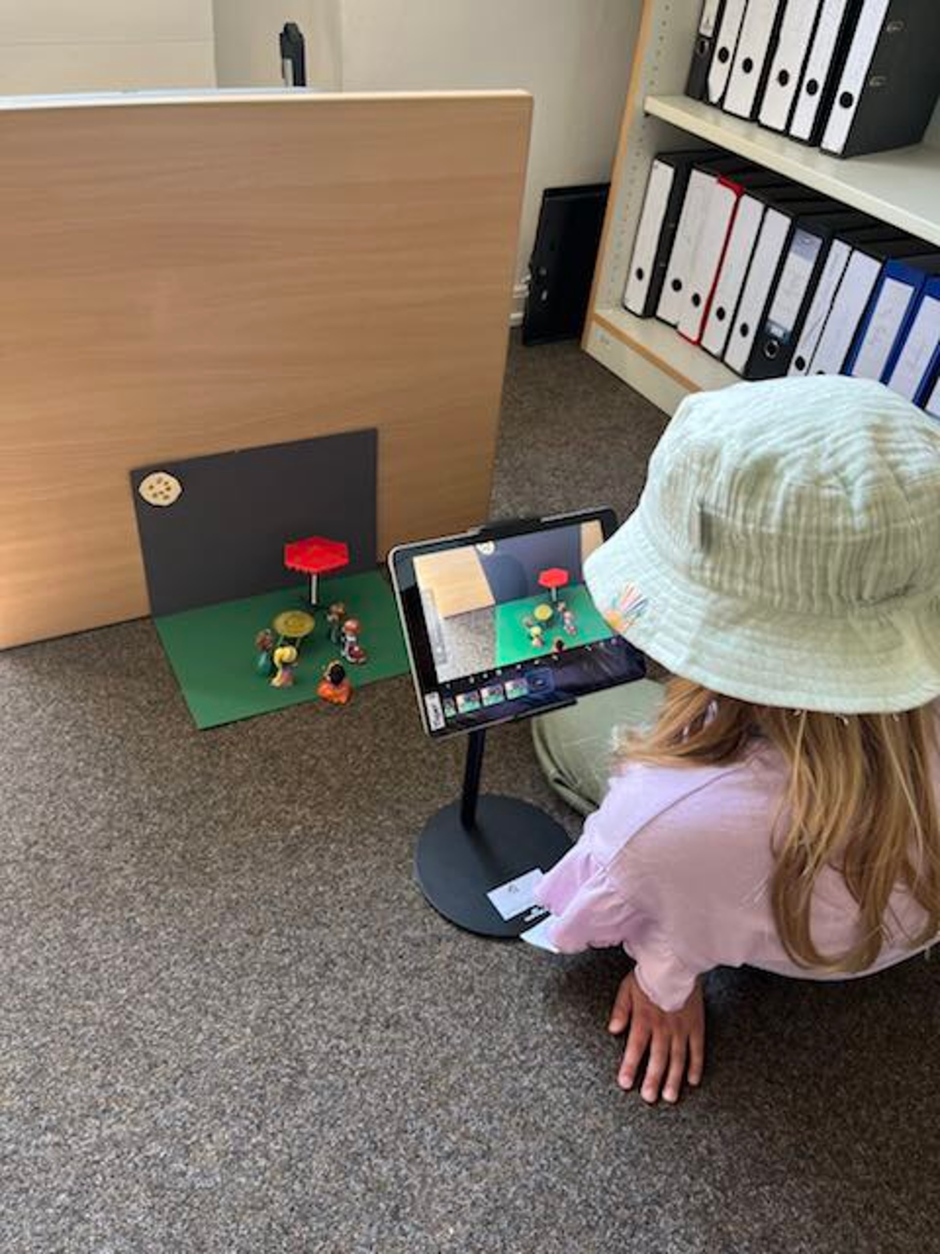 Ein Mädchen erstellt auf dem iPad und mit kleinen Figuren einen StopMotion-Film.