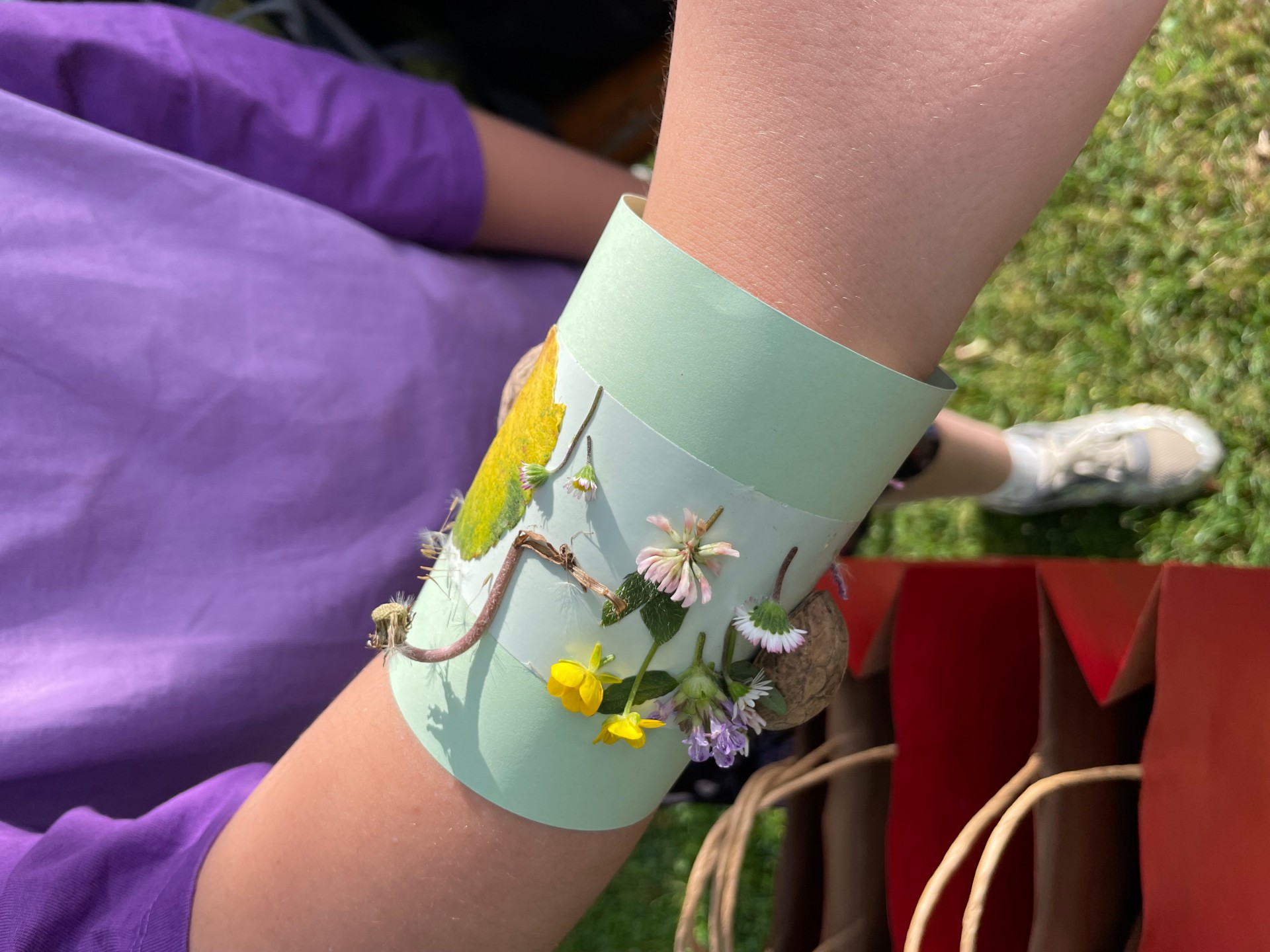 Ein Armband aus Pappe mit aufgeklebten Blumen.