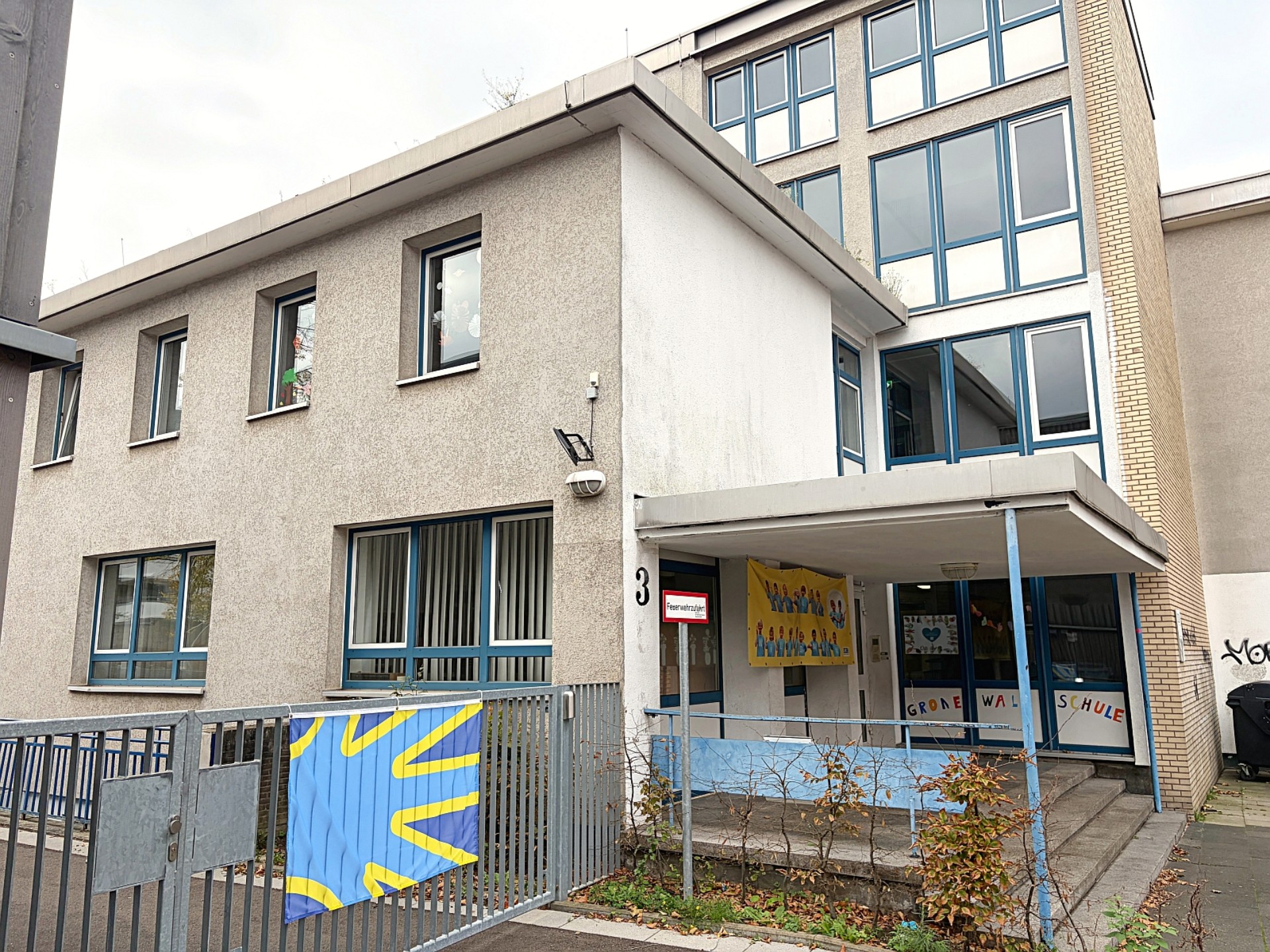 Blick auf Gebäude der Primarstufe, am Tor ist die Flagge der Gebärdensprache befestigt: eine stilisierte blaue Hand.