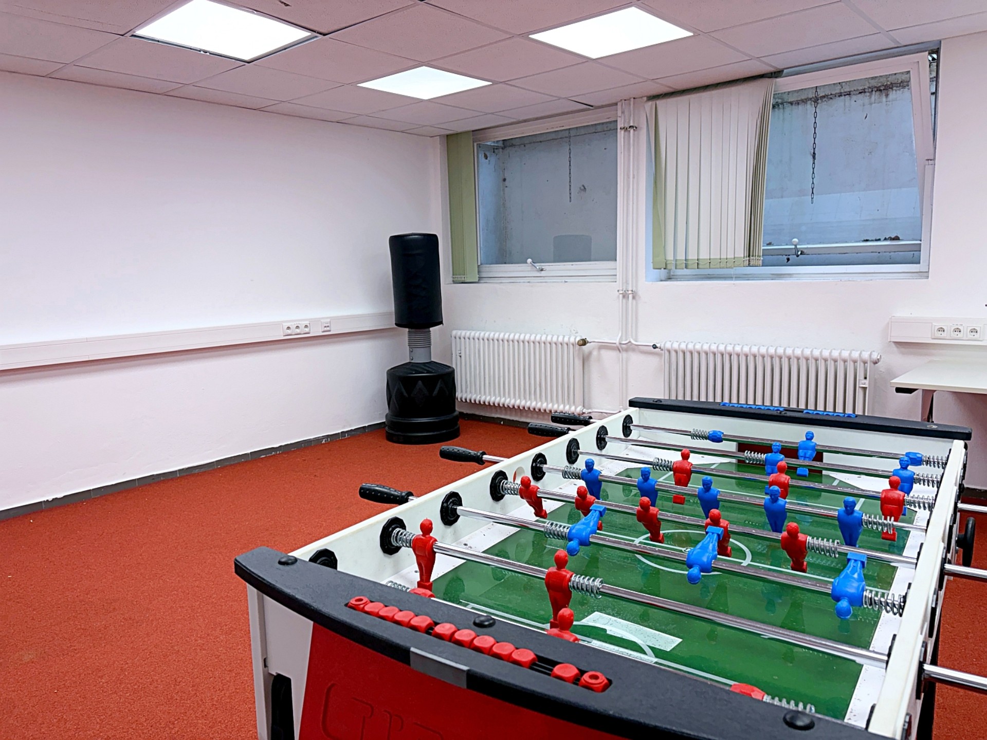 In einem Raum mit rotem Teppich steht ein Kicker-Tisch.