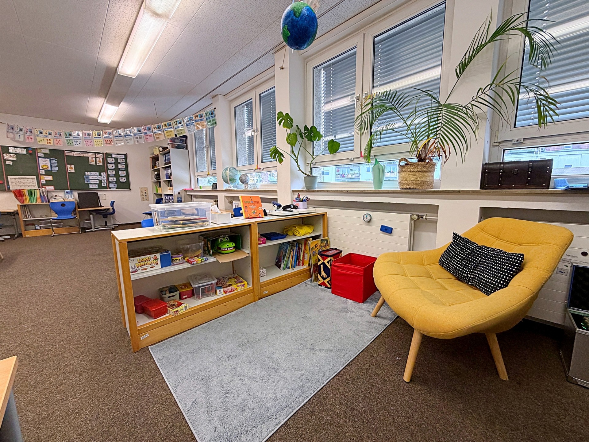 Vom Klassenzimmer durch ein halbhohes Regal mit Büchern abgeteilter Bereich zum Lesen