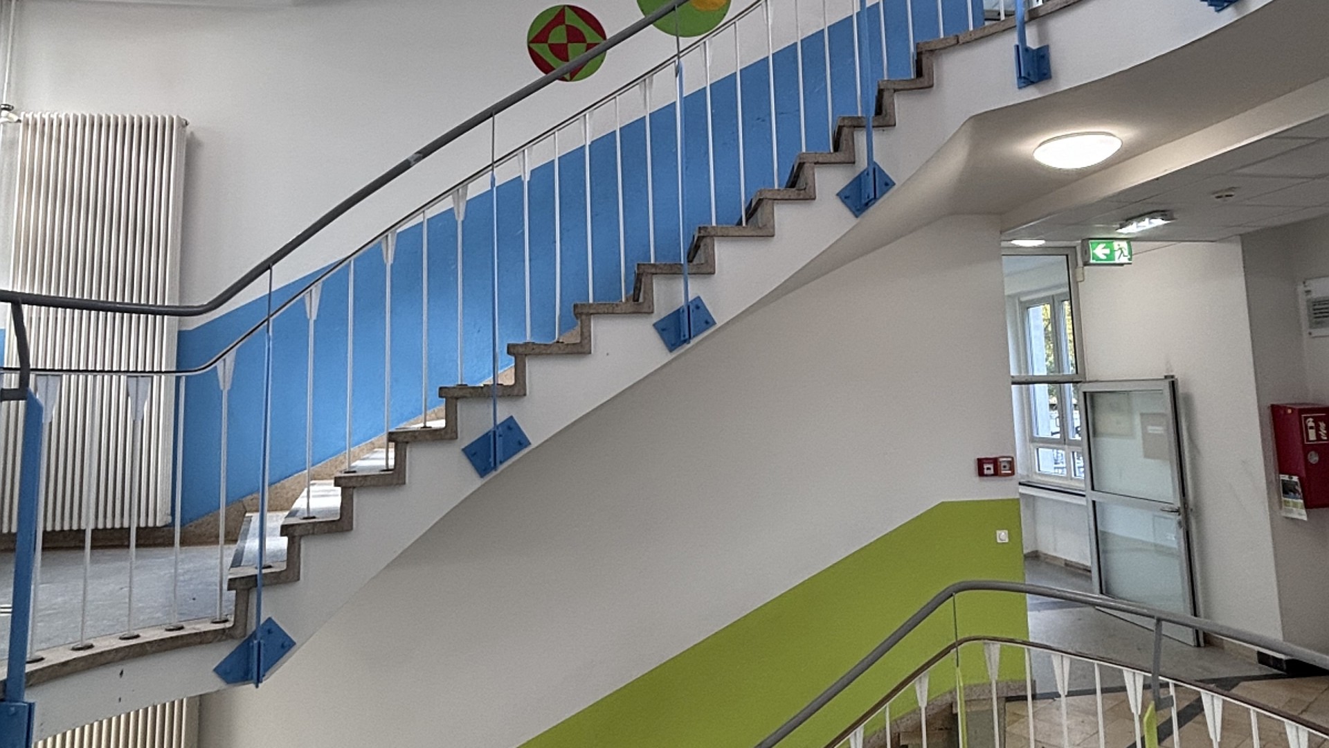 Blick in das Treppenhaus des Gebäudes in der Gronewaldstraße. Durch die Geländer sieht man, dass die Wände der einzelnen Etagen farblich markiert sind, grün, blau, rot.