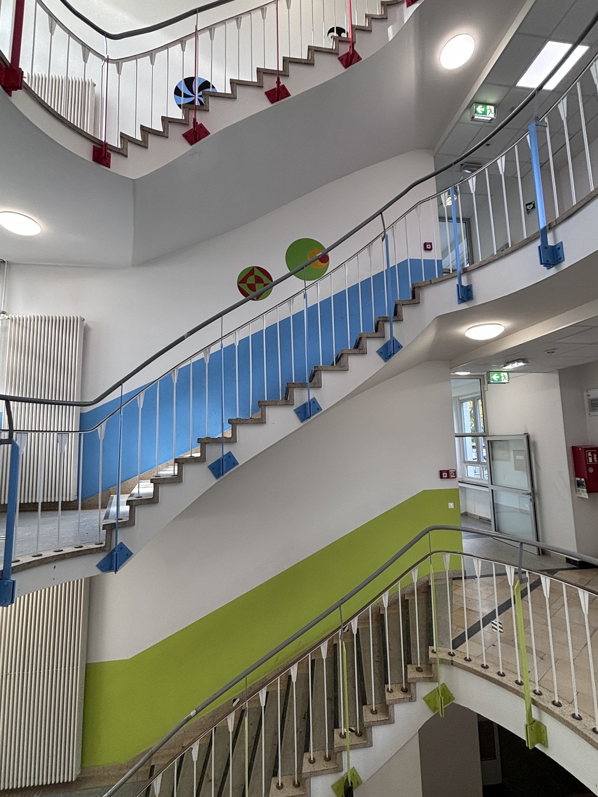 Blick in das Treppenhaus des Gebäudes in der Gronewaldstraße. Durch die Geländer sieht man, dass die Wände der einzelnen Etagen farblich markiert sind, grün, blau, rot.