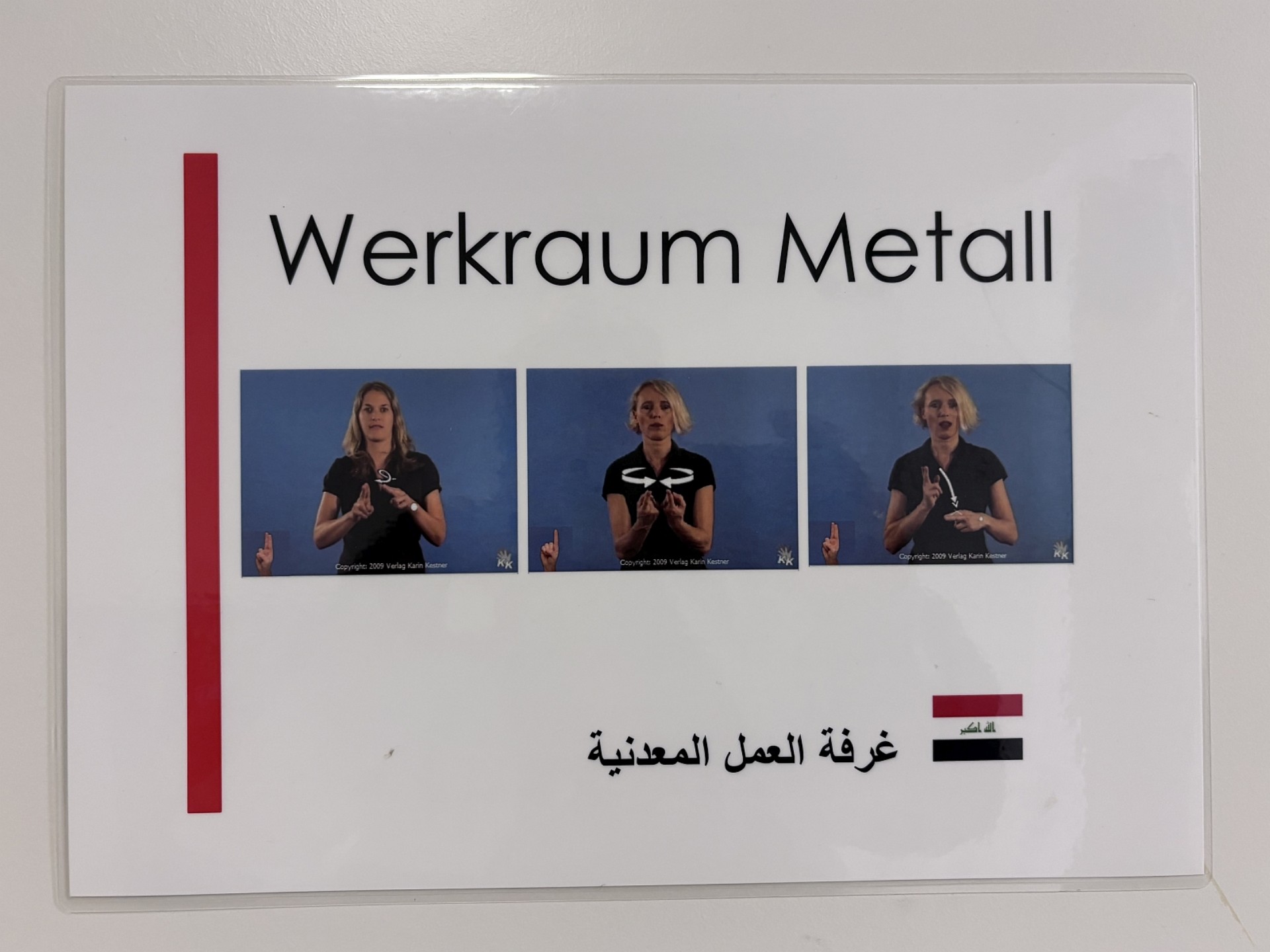 Schild "Werkraum Metall": In deutscher Schrift, als Gebärdenfotos und in arabischer Schrift inklusive Landesflagge von Iran.
