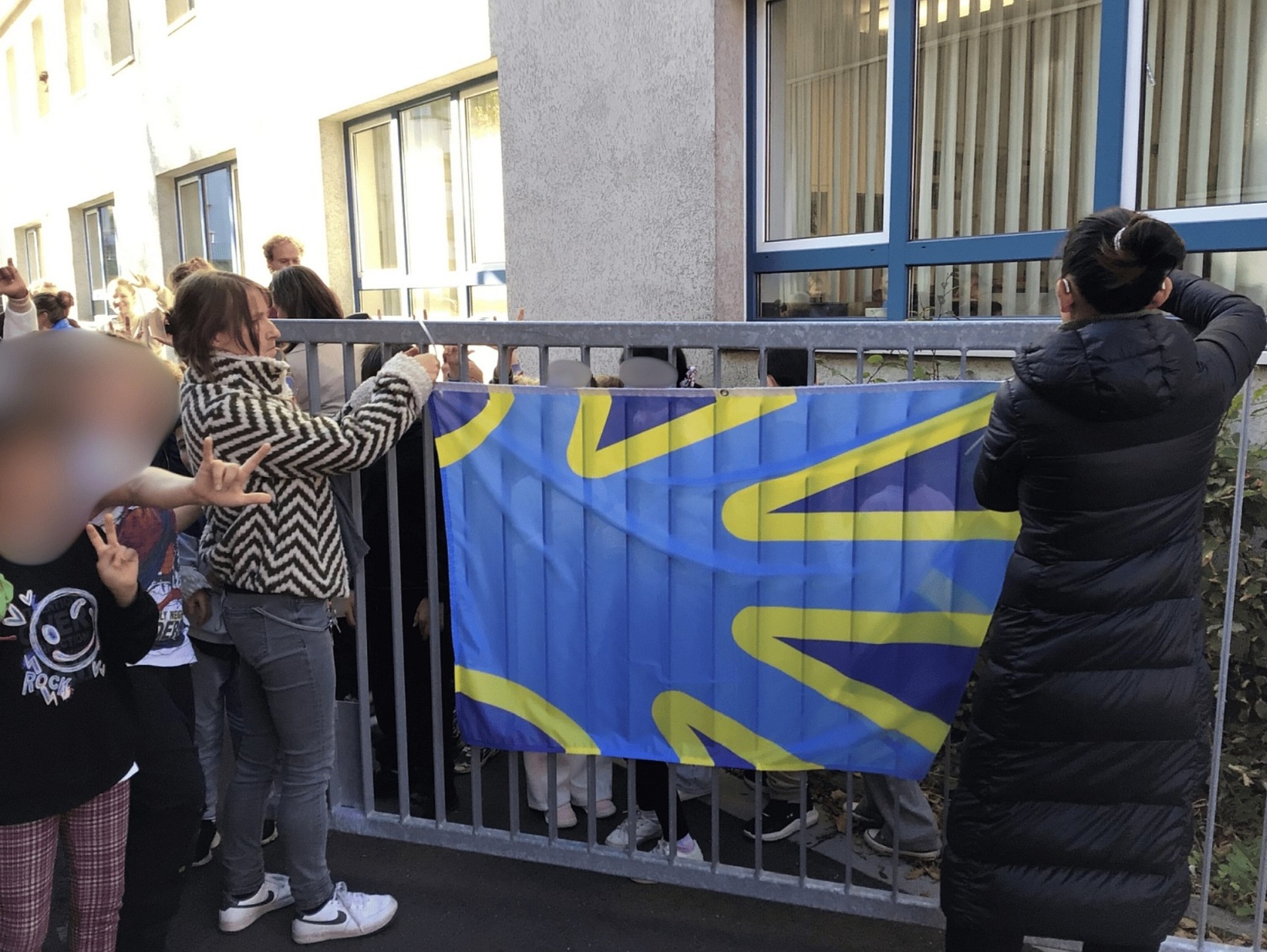 Zwei Frauen befestigen die Gebärden-Flagge am Schultor.